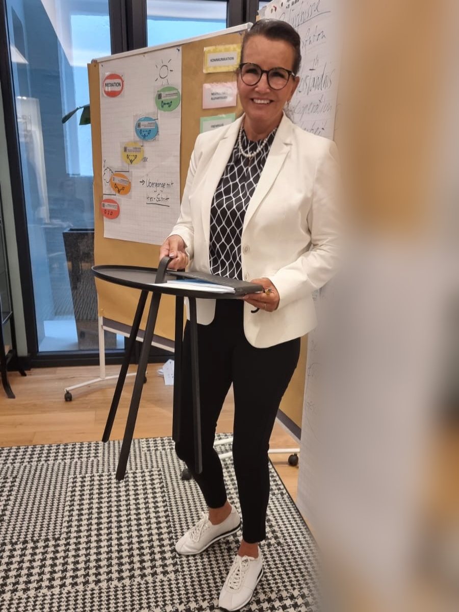Daniela Aigner-Seum richtet einen Seminarraum ein, dahinter Flipcharts und Moderationskarten