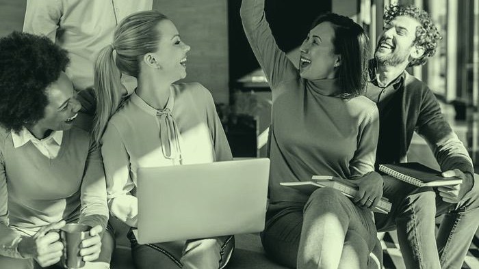 Team sitzt zusammen um einen Laptop und arbeitet